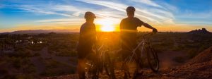 Two members of a family bike ride watch the sunset. 