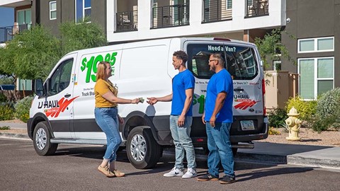A customer hands two moving labor Service Providers cash as a tip