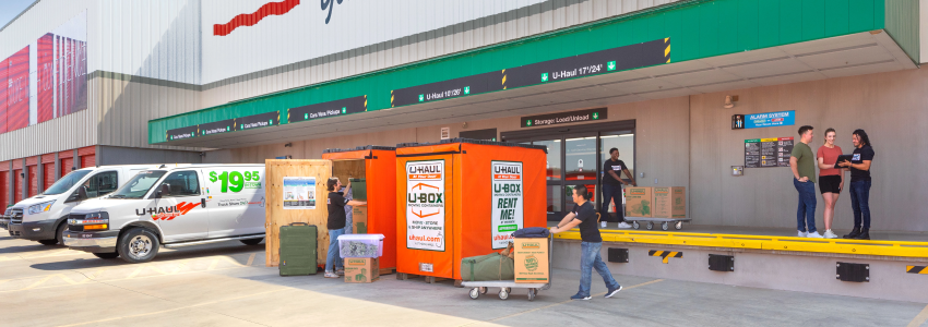 Movers help a couple unload their U-Box container at a U-Haul storage facility.