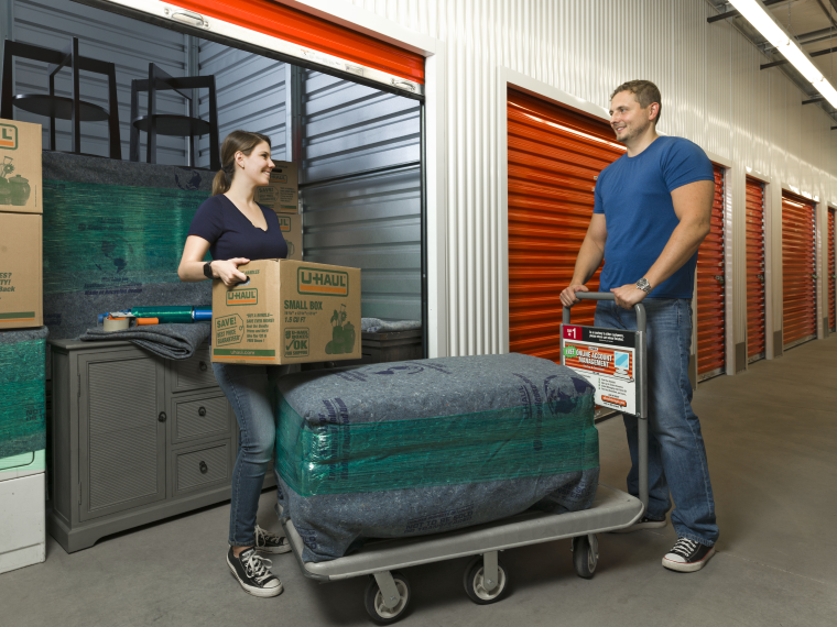 A couple moving things into a U-Haul self-storage unit.