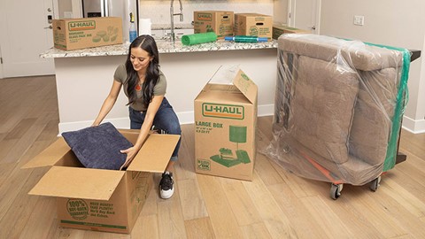 A woman packing a pillow into a U-Haul moving box