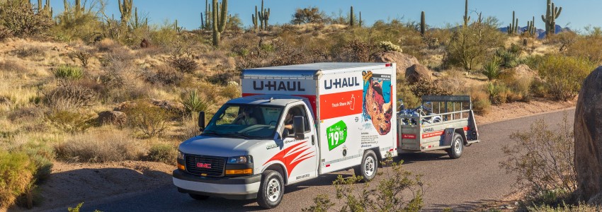 A U-Haul truck and trailer driving through the Arizona desert.