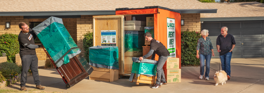 Movers helping an elderly couple move their belongings into a U-Box container.