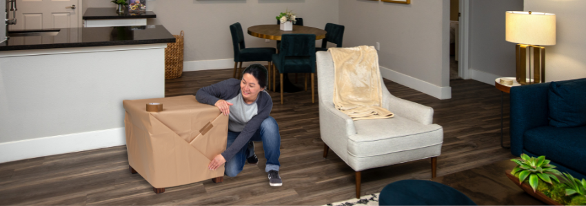 A woman wraps a side table in packing paper and secures it with packing tape.
