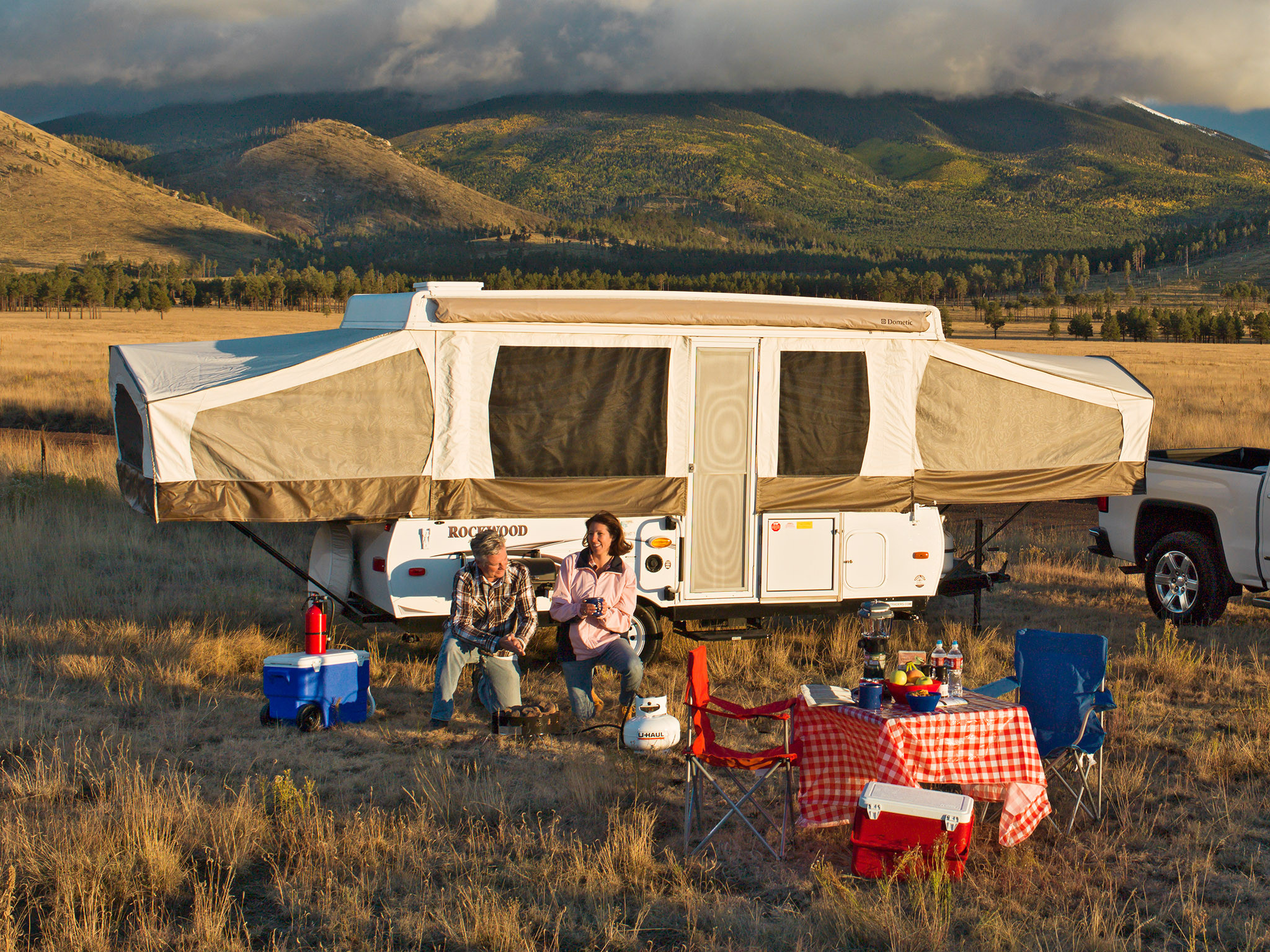 A couple is getting ready to cook a meal over a propane fire ring while camping.