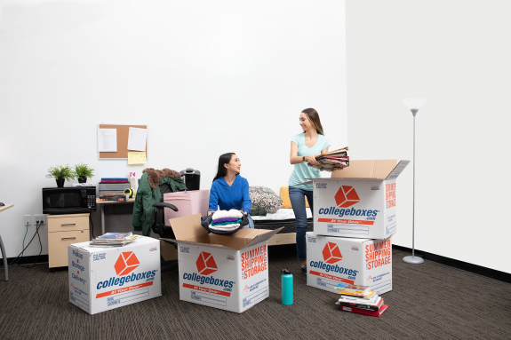 Two college students are unpacking their belongings in their new dorm room.