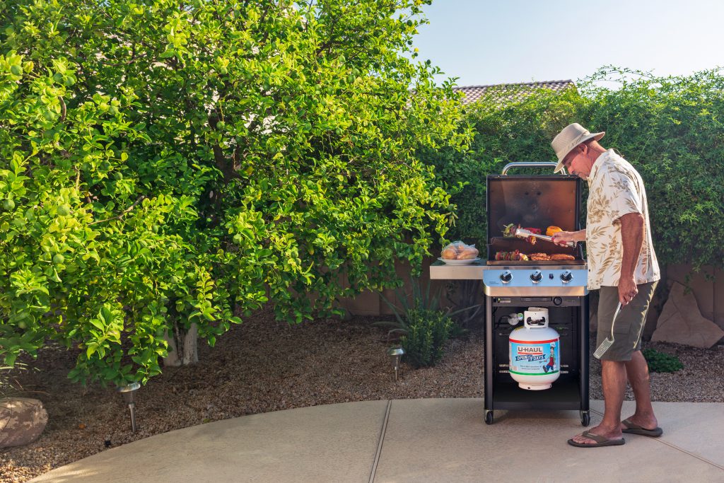 Man grilling outside with U-Haul propane.